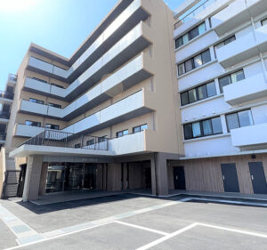 介護施設の建物外観。複数階建てで、1階に玄関・駐車スペースを備えた近代的な構造